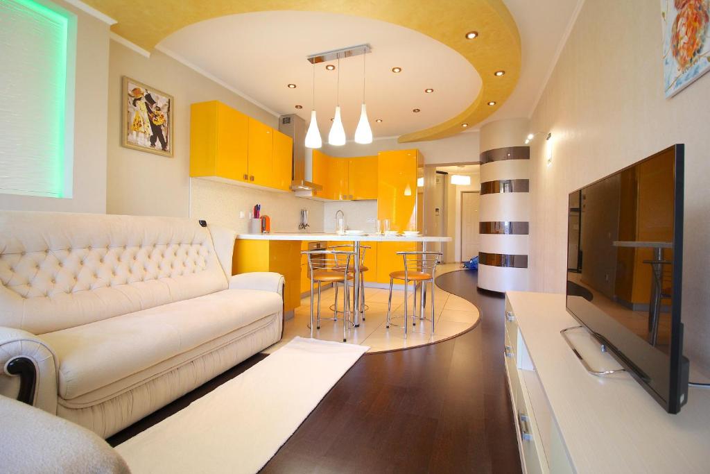 a living room with a couch and a kitchen with yellow cabinets at a Apartments by SeaPort in Sochi