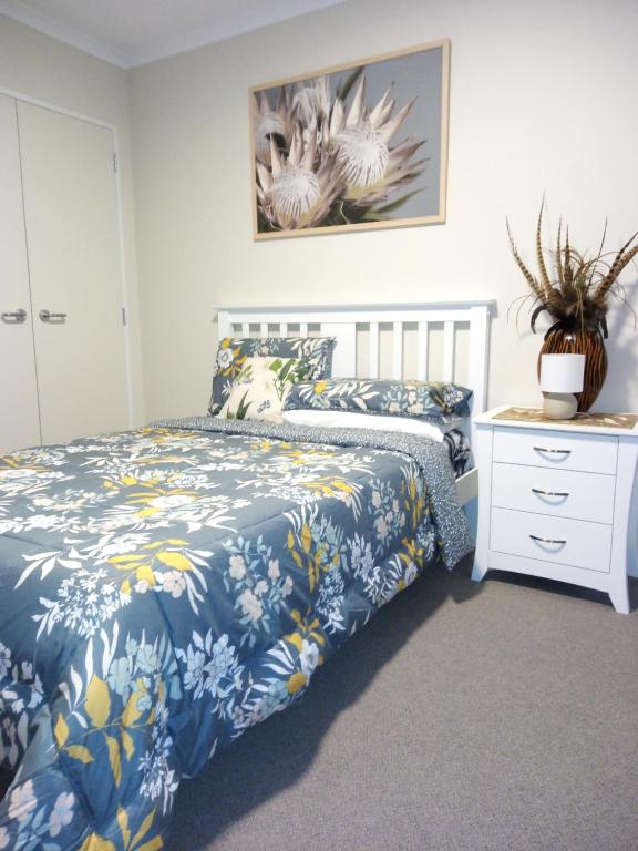 a bedroom with a bed with a blue and white bedspread at NORTH SHORE HOMESTAY Auckland in Auckland