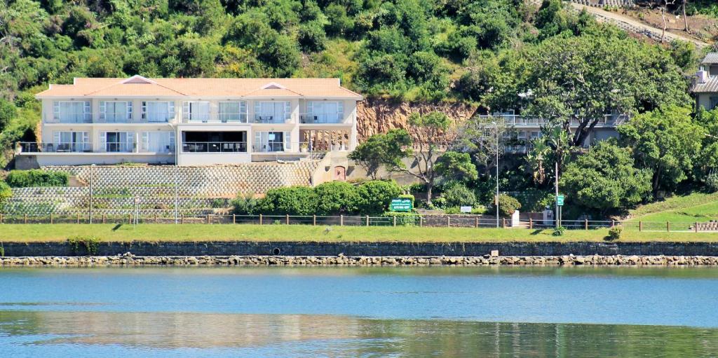 a large house sitting on the side of a river at Phoenix Lodge and Waterside Accommodation in Knysna