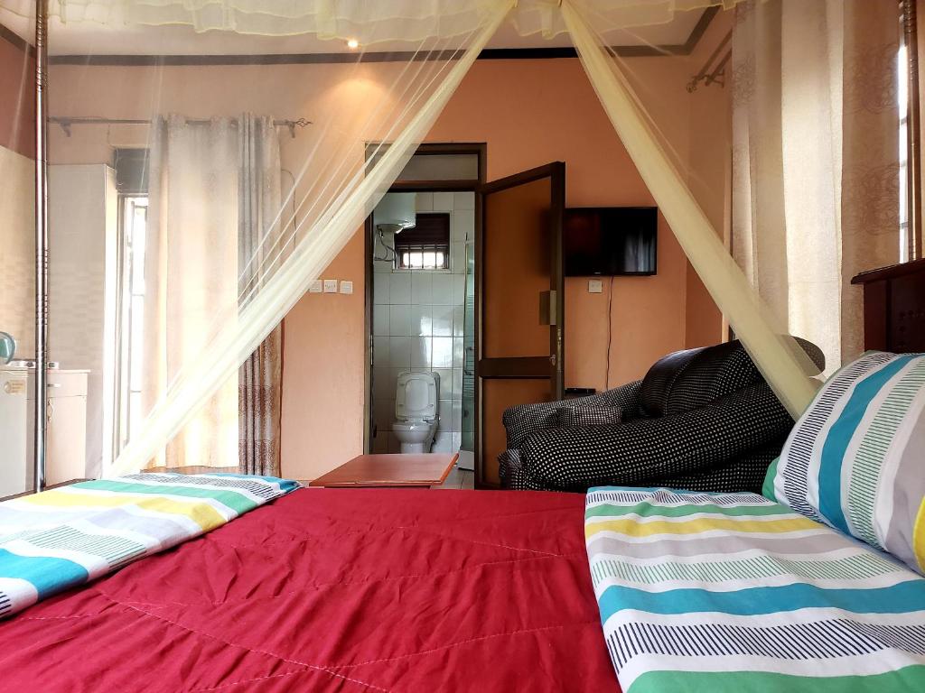 a bedroom with a bed with a red blanket at TGS Homestay in Kampala