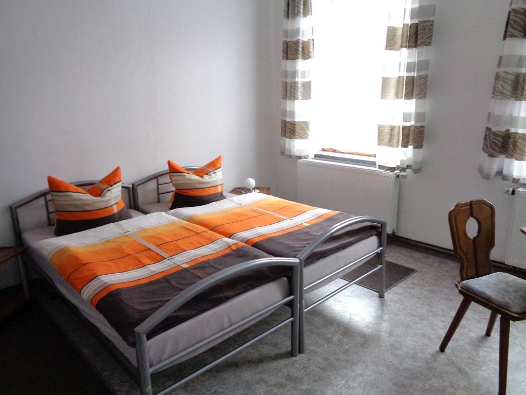 a bedroom with a bed with orange sheets and a window at Pension Bahnmeister in Probstzella