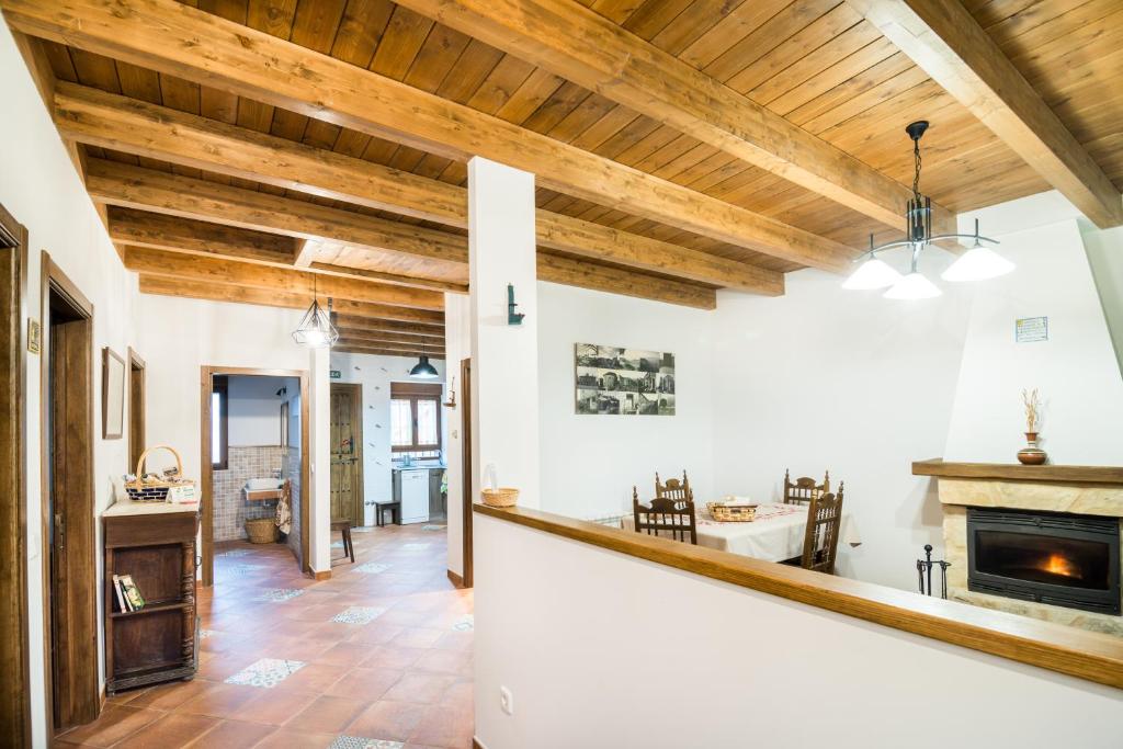 Casa Rural LAS ABUBILLAS في Mirabueno: غرفة معيشة مفتوحة مع سقوف خشبية ومدفأة