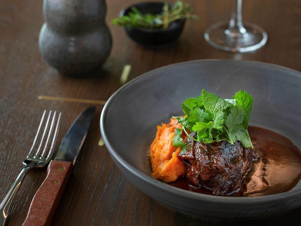 a bowl of food with meat and greens on a table at Novotel Auckland Airport in Auckland