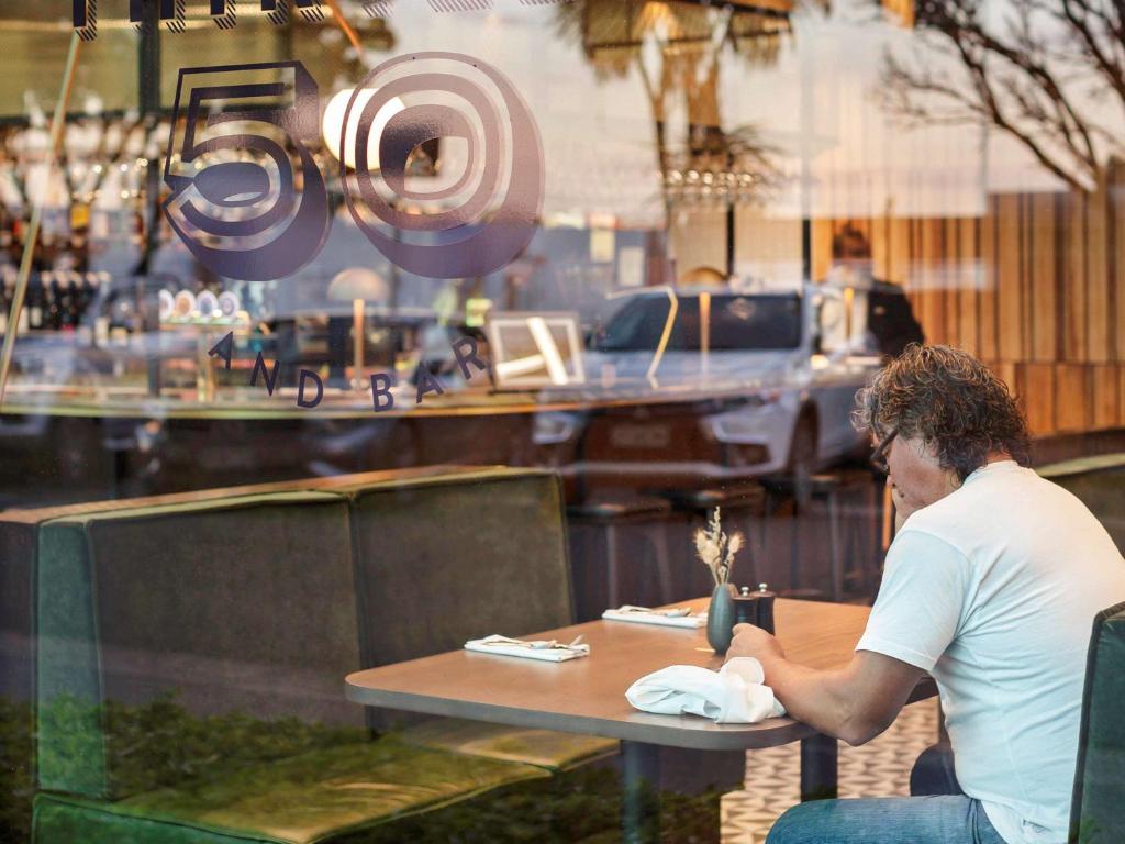 a man sitting at a table in a restaurant at Novotel Auckland Airport in Auckland