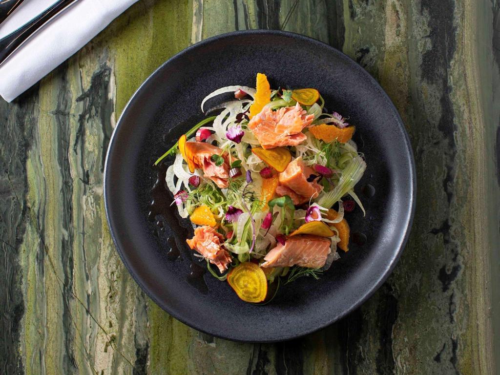 a black plate with a salad on a table at Novotel Auckland Airport in Auckland