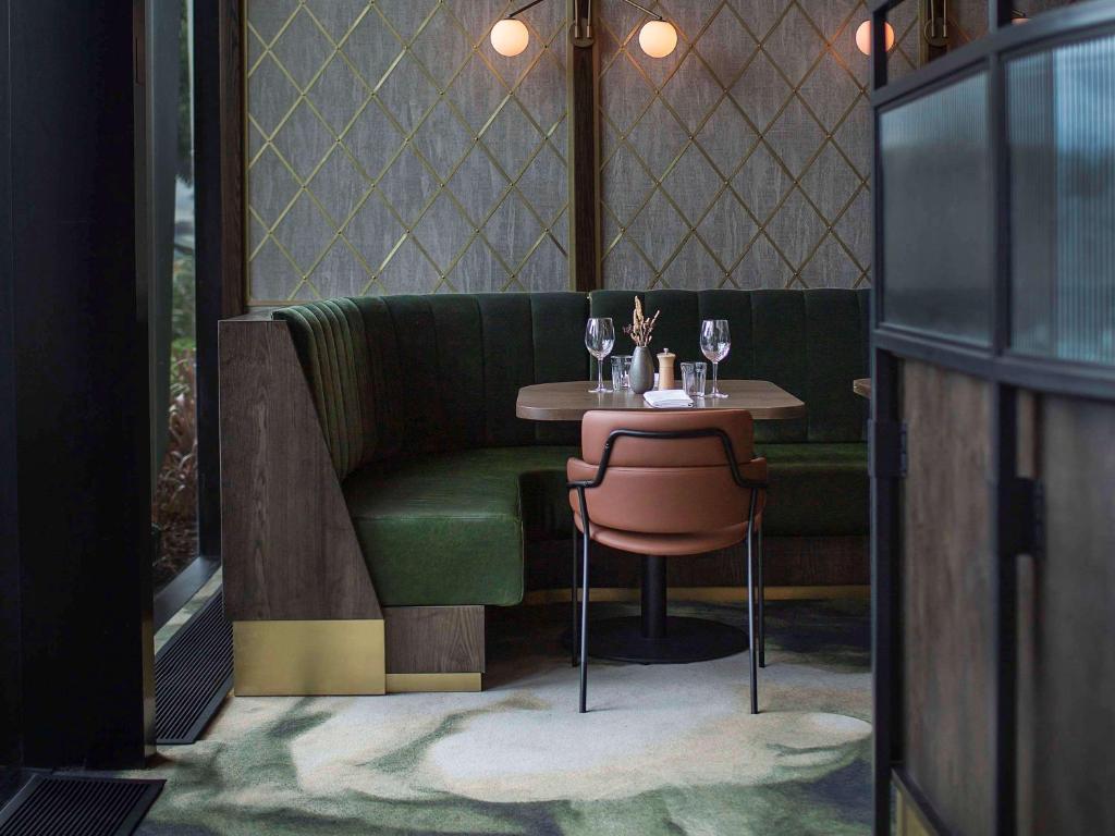 a table with a green couch and a small table with wine glasses at Novotel Auckland Airport in Auckland