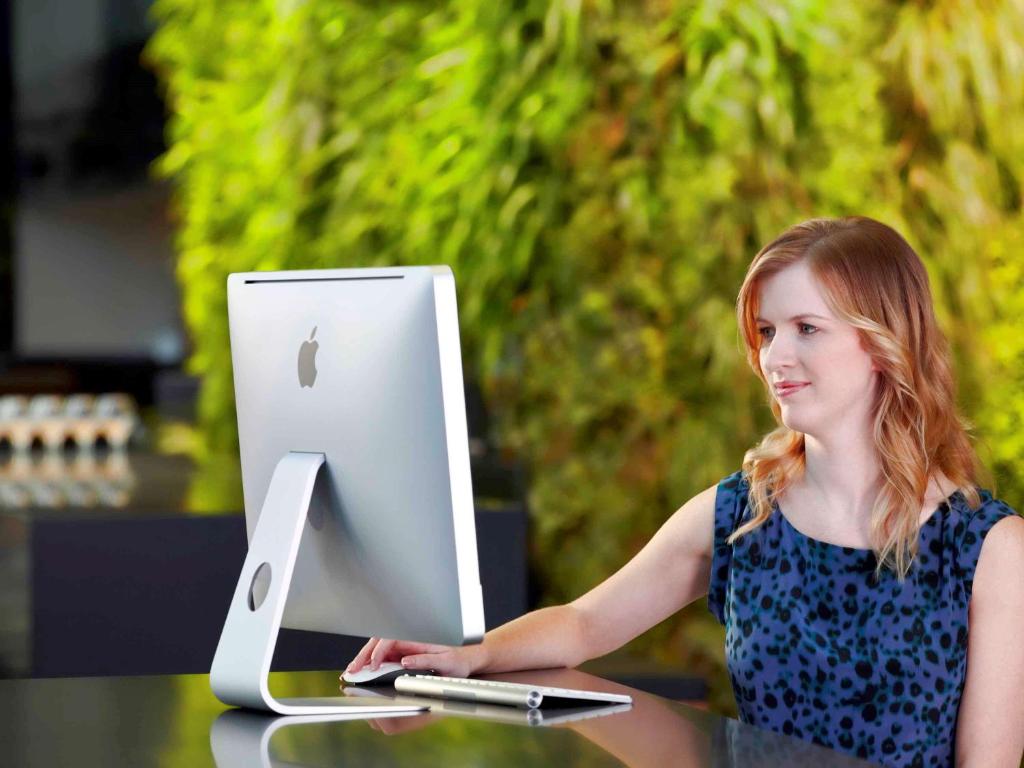 a woman sitting at a table with a laptop computer at Novotel Auckland Airport in Auckland