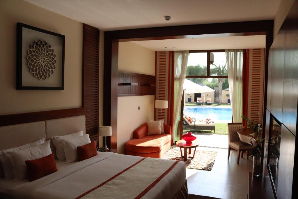 a bedroom with a bed and a living room with a pool at Western Hotel - Madinat Zayed in Madīnat Zāyid