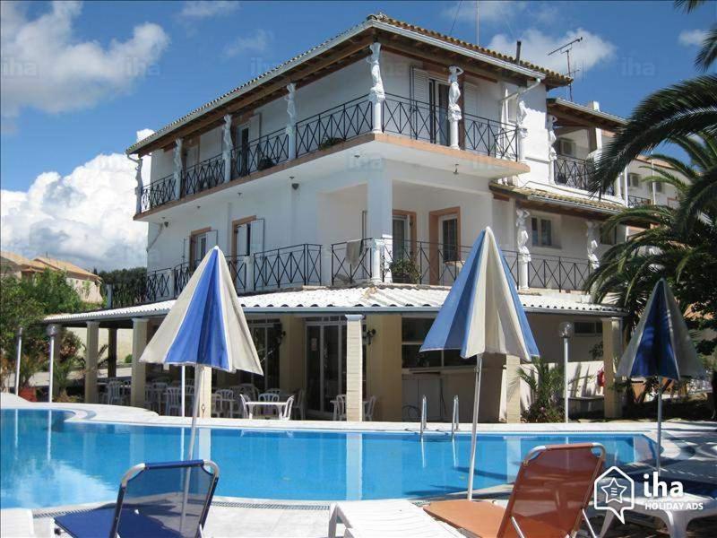 a large house with a swimming pool and two umbrellas at Elena-Stella Apartments Arillas Corfu in Arillas