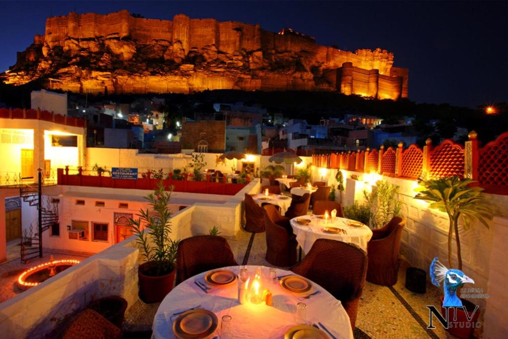 ein Restaurant mit Tischen und Stühlen mit einem Schloss im Hintergrund in der Unterkunft Krishna Prakash Heritage Haveli in Jodhpur