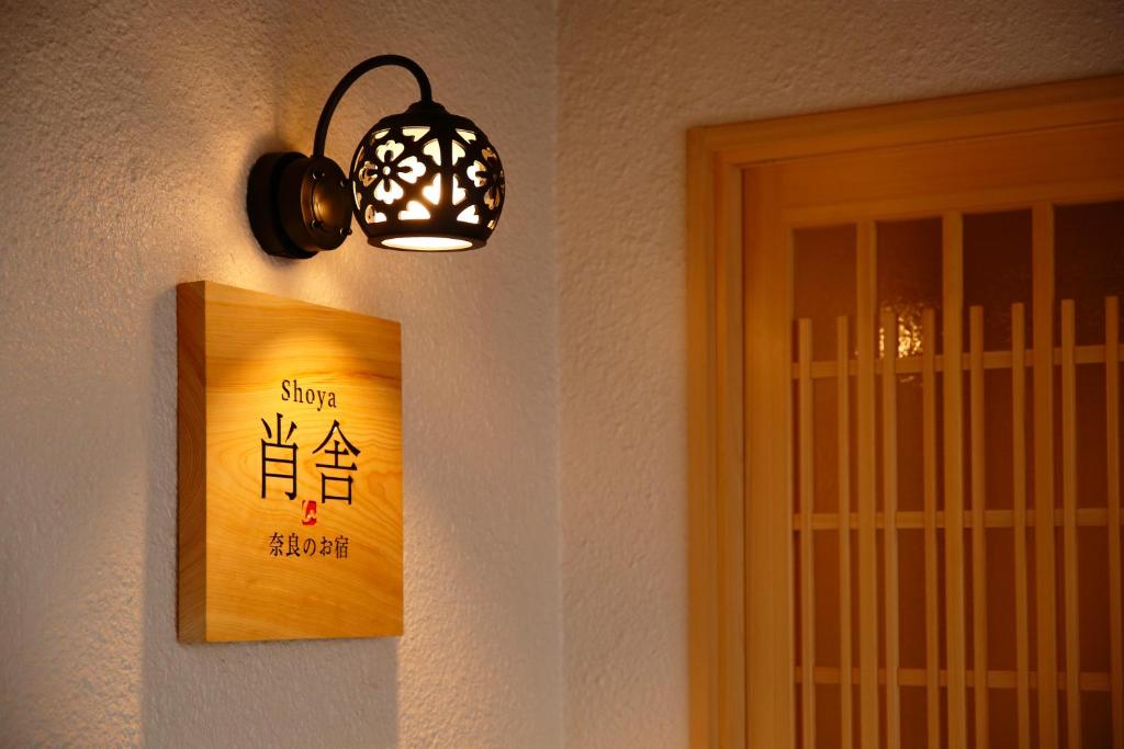 una luz colgando en una pared junto a una puerta en 肖舎 Shoya en Nara