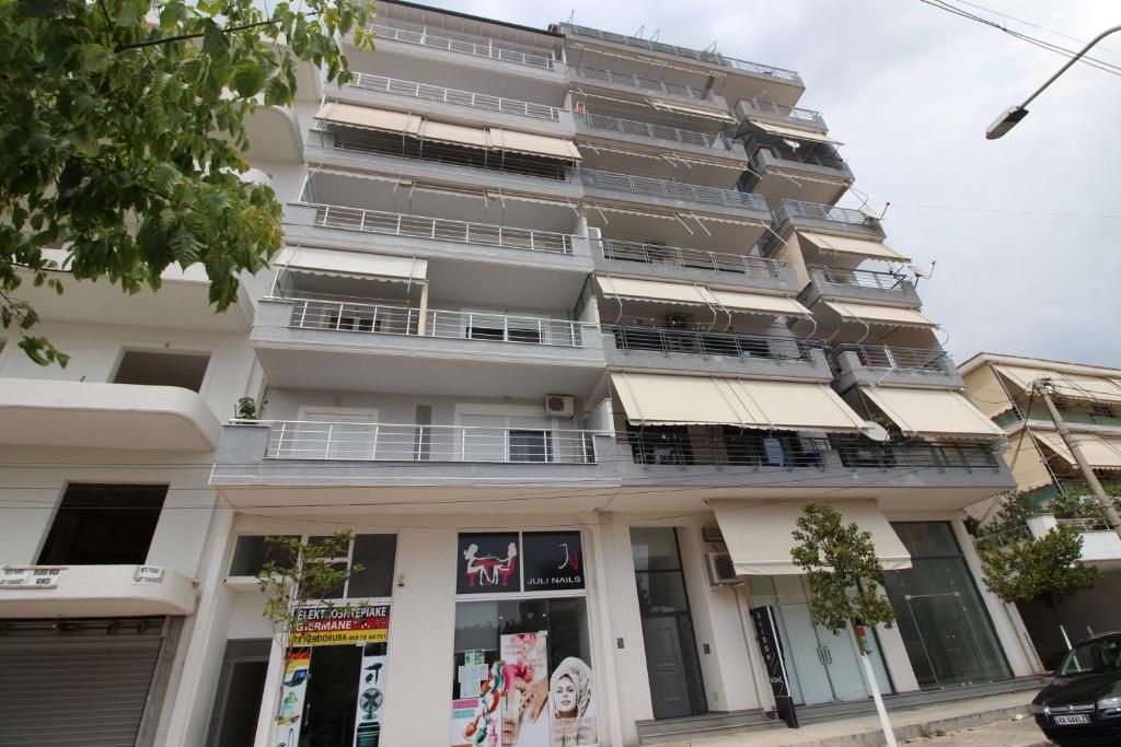 a tall white building with balconies on a street at Mona`s apartments 1 in Sarandë
