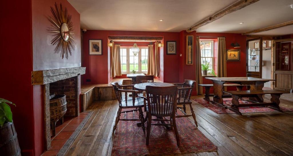 a dining room with red walls and a table and chairs at The Brisley Bell in Brisley