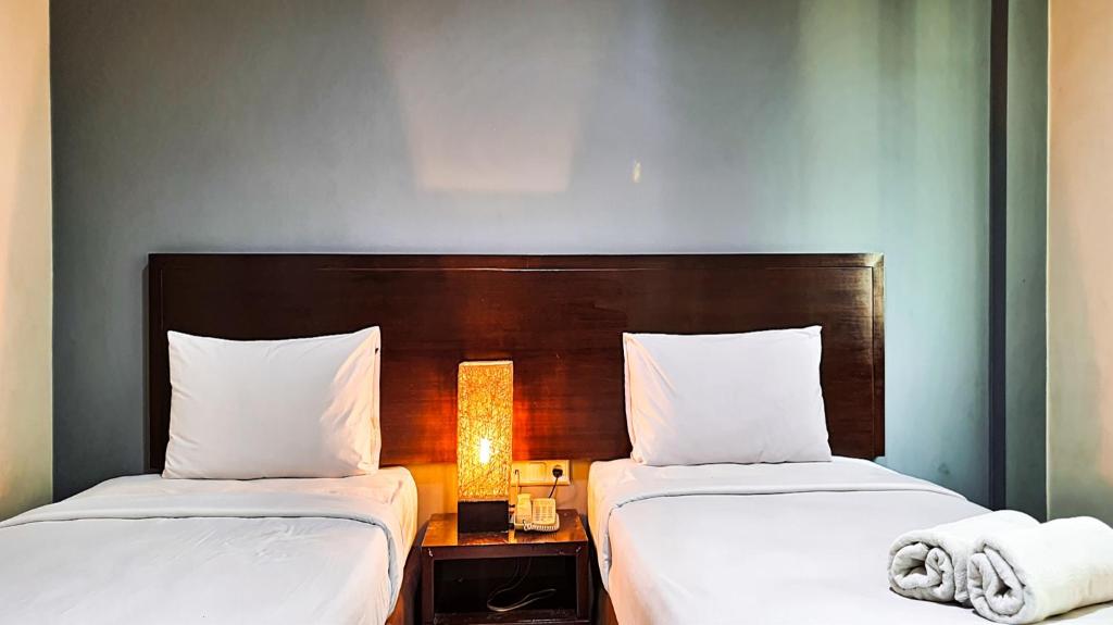two beds sitting next to each other in a room at N1 Hotel Tanah Abang in Jakarta