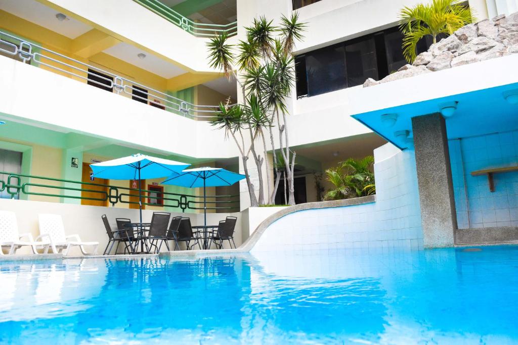 a swimming pool with chairs and umbrellas next to a building at Blue Bay Hotel in Salinas