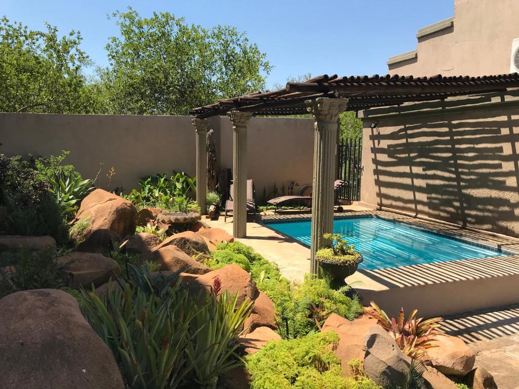 a swimming pool in a garden with a pergola at Komati Kruger Villas in Komatipoort