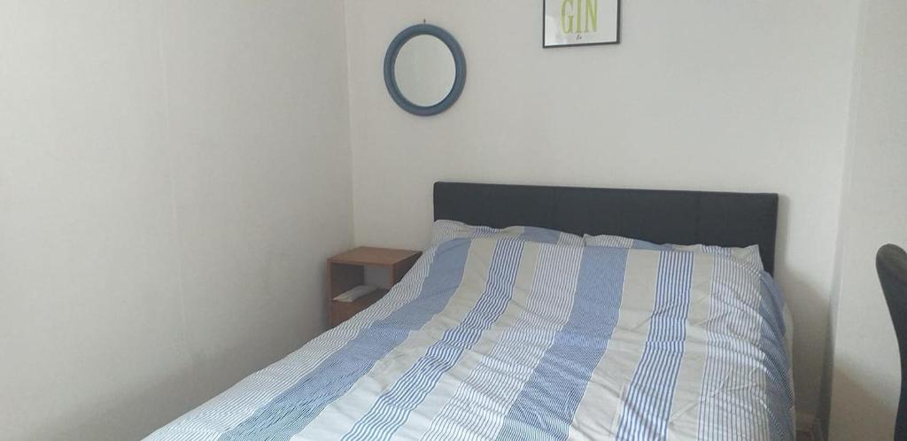 Large double room or single room with shared bathroom في آش: سرير مع لحاف مخطط باللون الأزرق والأبيض ومرآة