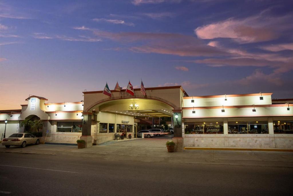 un edificio con un estacionamiento con banderas dentro en Hotel San Martin, en Hermosillo