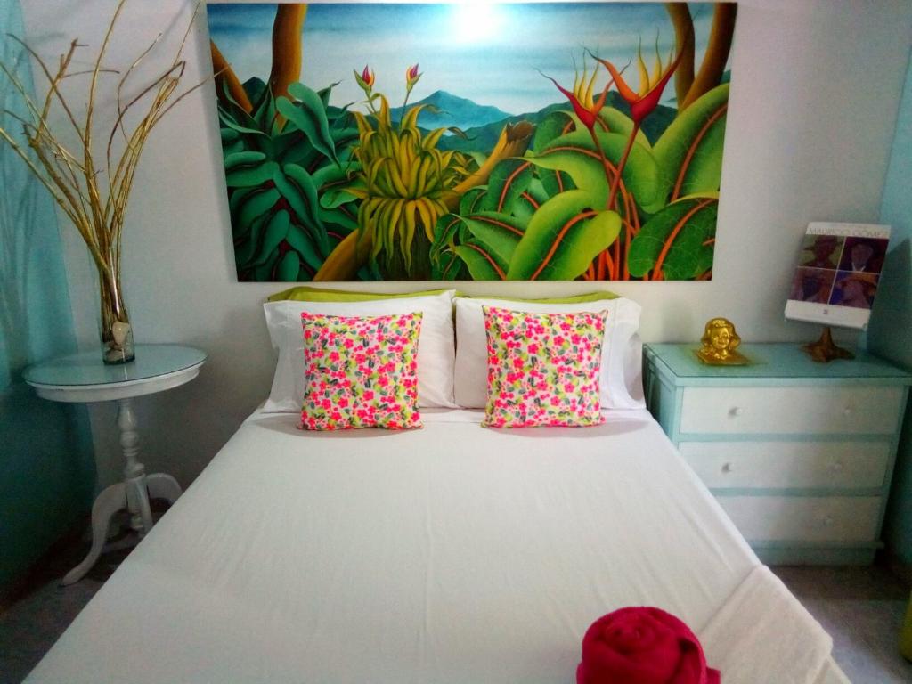 a bedroom with a white bed with a painting on the wall at Casa Del Pintor in Santa Marta