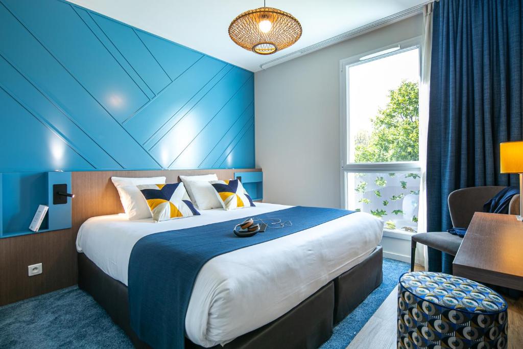 a hotel room with a large bed and a window at Hotel Restaurant Saint James, Montaigu-Vendée The Originals Boutique in Montaigu-Vendée