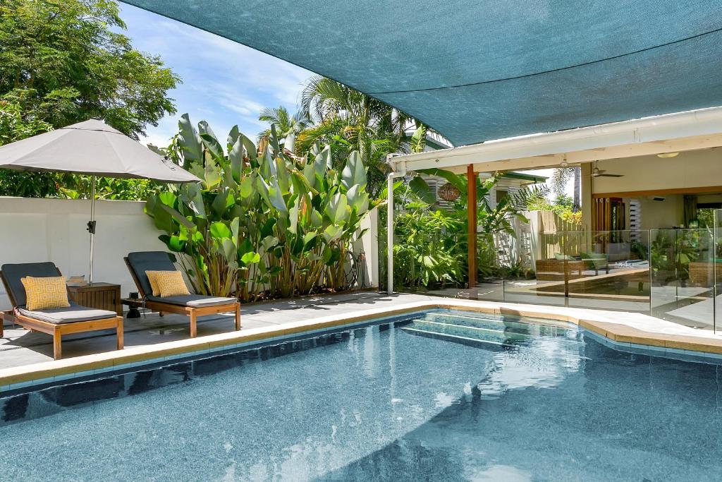 a swimming pool with two chairs and an umbrella at Vista Hillview Family Villa in Stratford