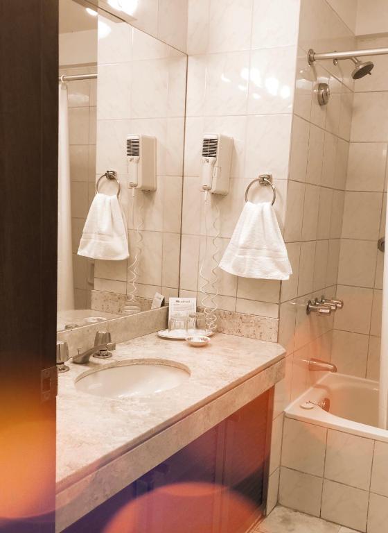 a bathroom with a sink and a mirror and a tub at Hotel Boulevard in Lima