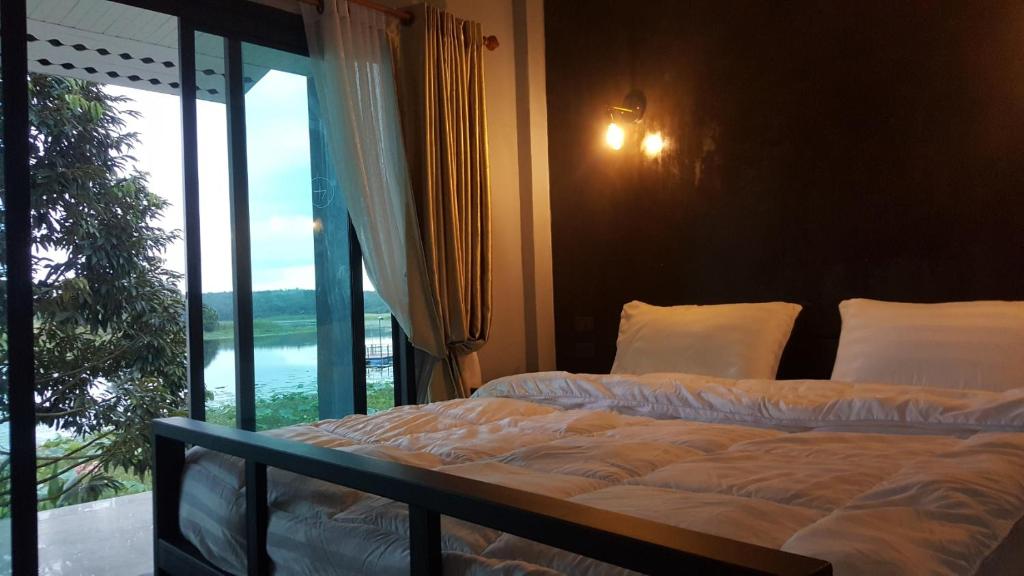 1 dormitorio con 2 camas y ventana grande en บาย เดอะแดม คาเฟ่ แอนด์ ฟาร์มสเตย์ By the dam Cafe and Farmstay, en Plai Phraya