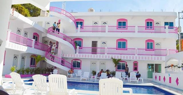 um edifício com varandas cor-de-rosa e brancas e uma piscina em Hotel Real Da Vinci em Acapulco