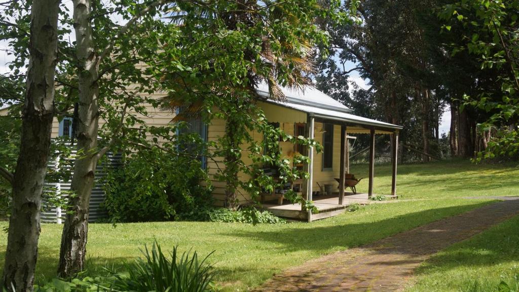 una pequeña casa blanca con porche en el césped en Colby Cottages, Wooragee near Beechworth, en Wooragee