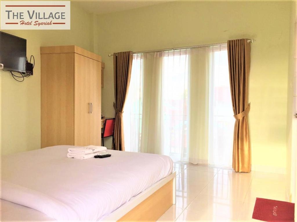 a bedroom with a white bed and a window at Hotel The Village Syariah in Pekanbaru