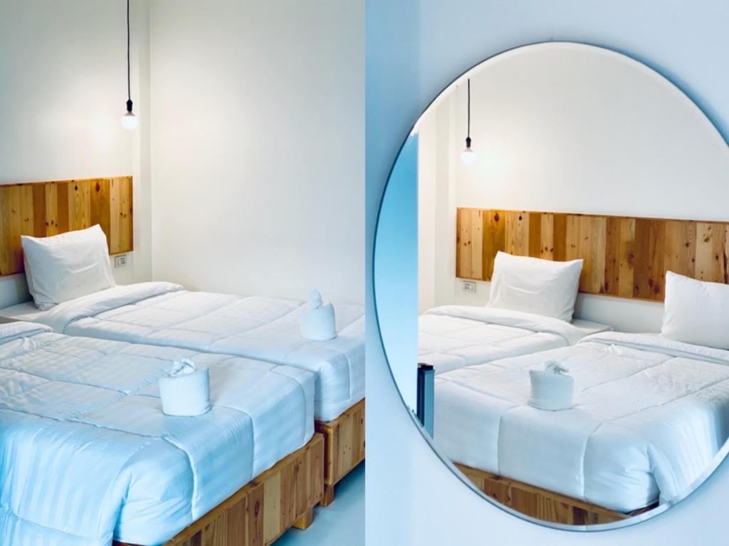 2 Betten in einem Zimmer mit Spiegel in der Unterkunft Loei Station in Loei