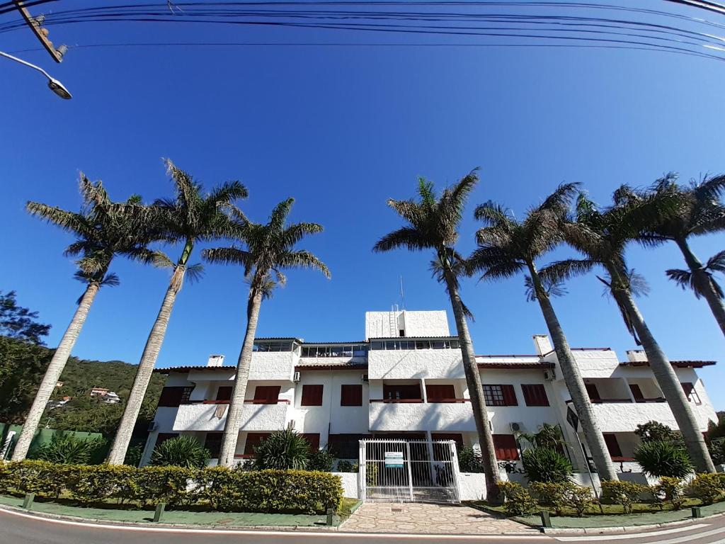 um edifício com palmeiras em frente em Residencial Hostal Blanco em Florianópolis
