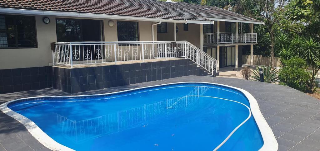 a blue swimming pool in front of a house at Tertius Lodge And House in Nelspruit