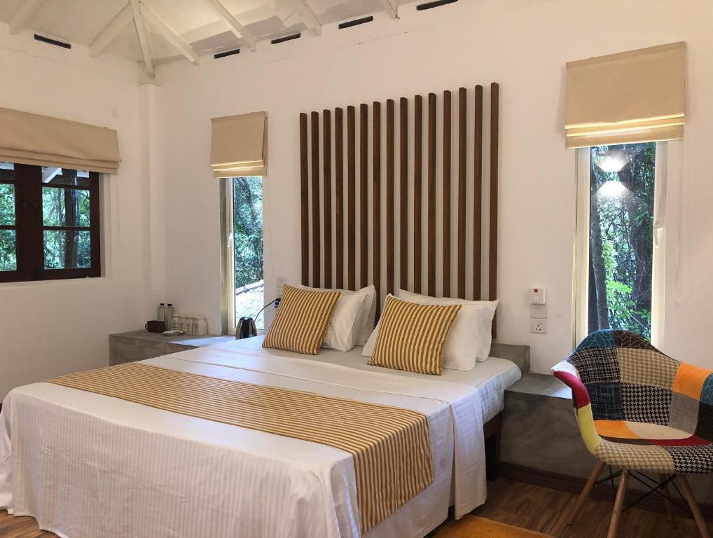 a bedroom with a large bed and two chairs at River Garden Resort in Belihul Oya