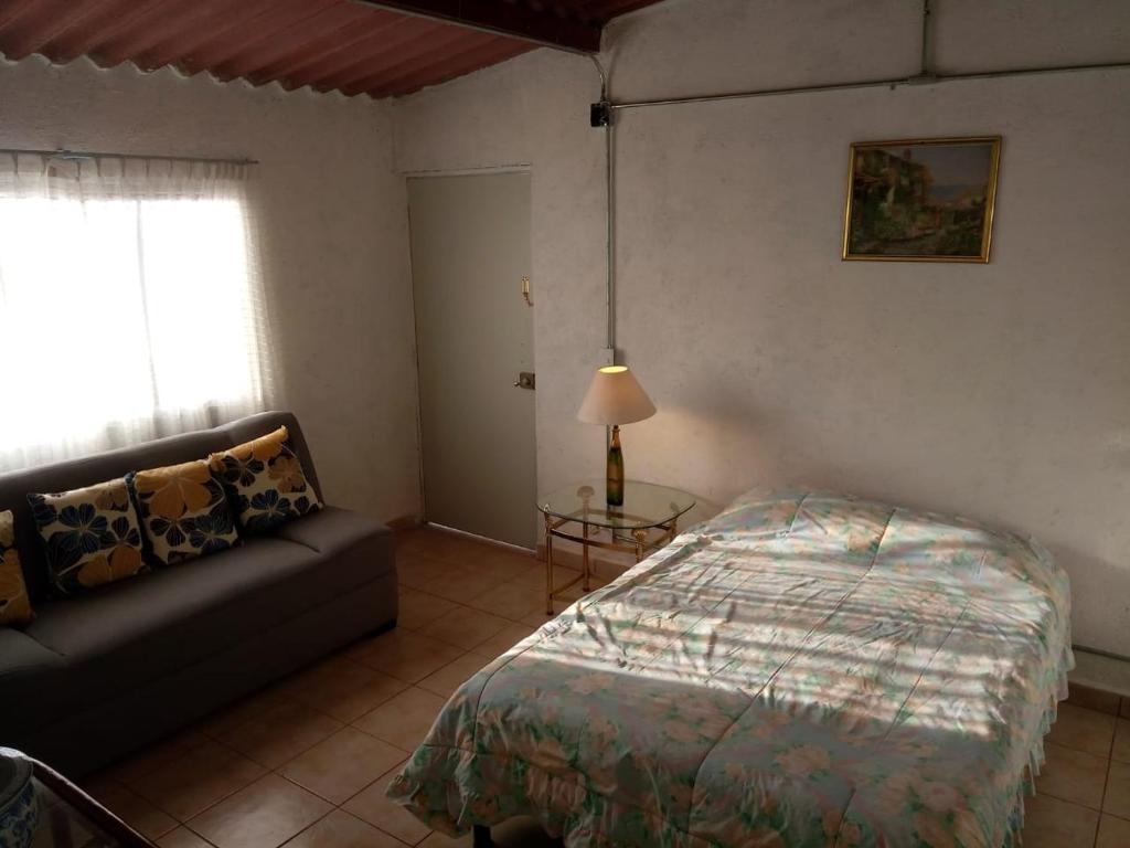 a bedroom with a bed and a couch and a window at Casa de Irma para visitar la ciudad o de negocios in Mexico City