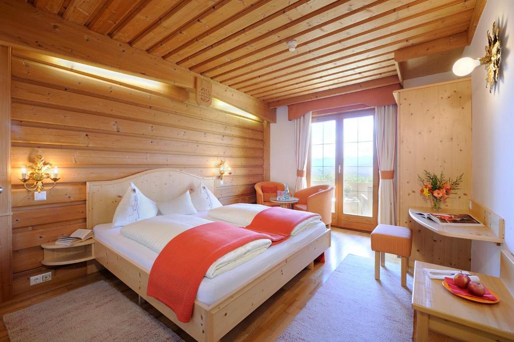 ein Schlafzimmer mit einem Bett in einem Zimmer mit Holzwänden in der Unterkunft Naturhotel Alpenrose in Millstatt