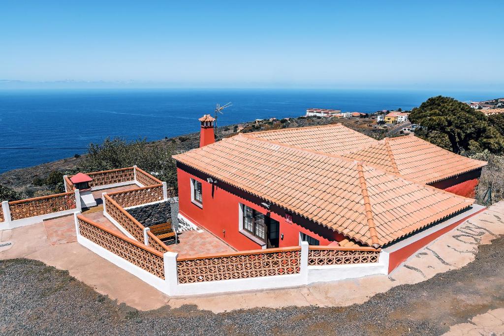 CASA VILA في Garafía: منزل احمر على قمة تل مع المحيط