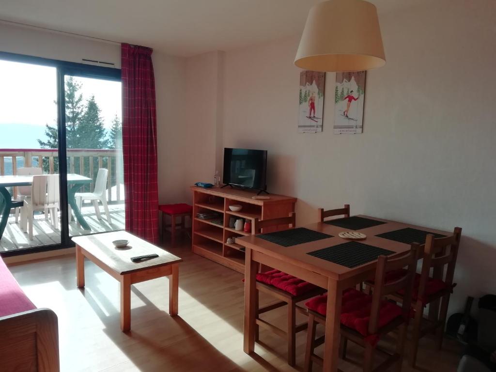 een woonkamer met een eettafel en een televisie bij Font-Romeu près des pistes - Appartement 2 pièces très lumineux avec terrasse et vue panoramique in Font Romeu Odeillo Via