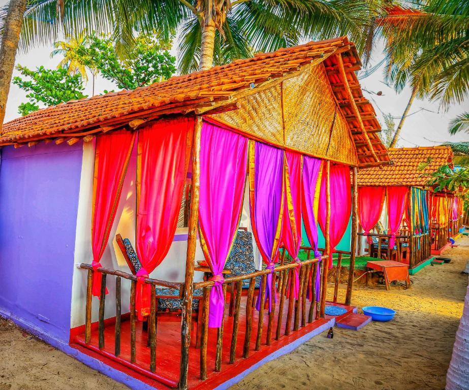 a small house with colorful curtains on a beach at GoYm Resort in Arambol