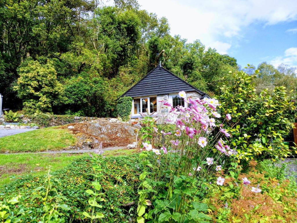 a small house in a garden with flowers at Granite Croft in Appin