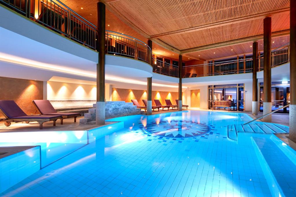 a large swimming pool in a building with a building at Ayurveda Resort MANDIRA in Bad Waltersdorf