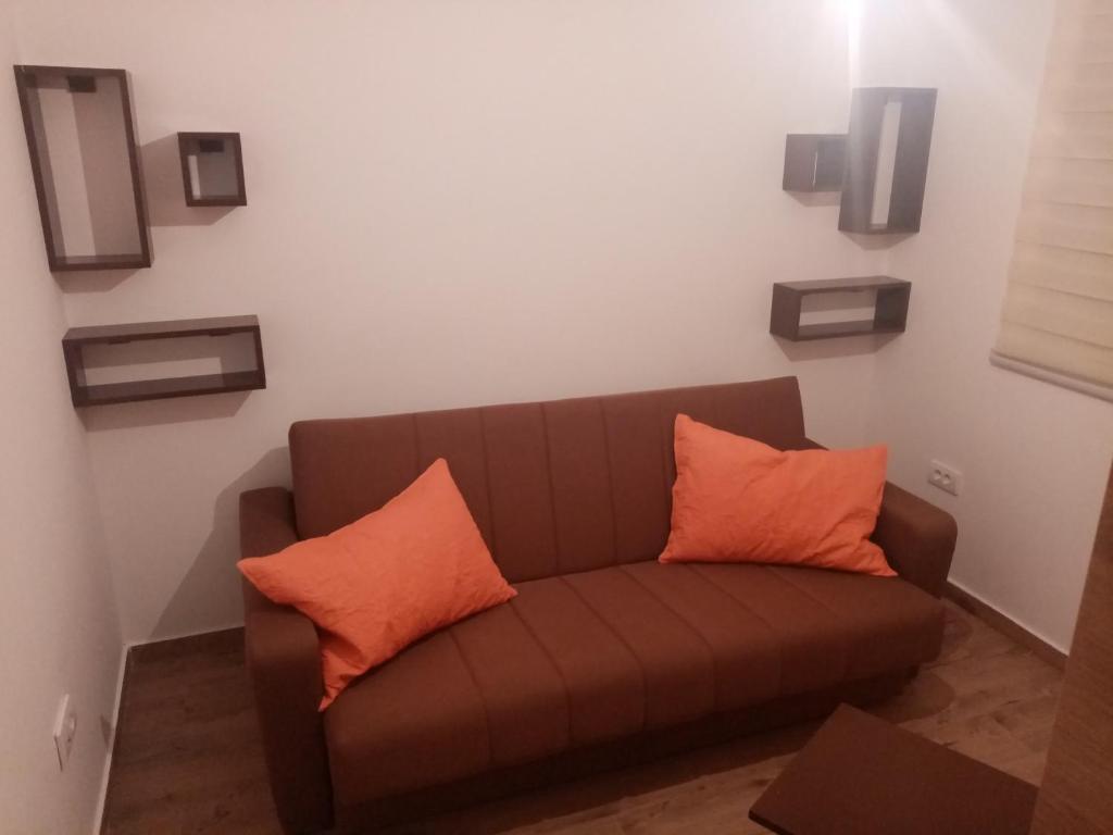 a brown couch with two orange pillows in a room at Iznad oblaka A1 in Kopaonik