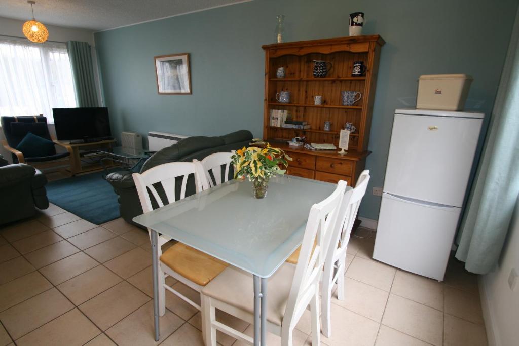 a kitchen with a table and chairs and a refrigerator at Freshwater Bay Holiday Cottages in Pembroke