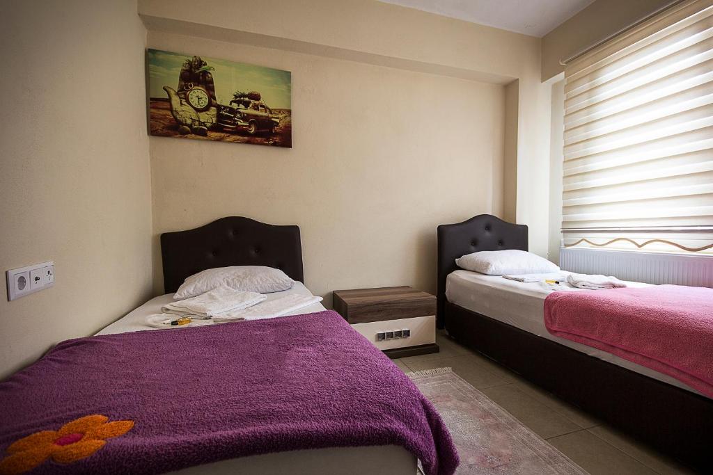 1 dormitorio con 2 camas, mantas moradas y ventana en HOTEL 22, en Edirne