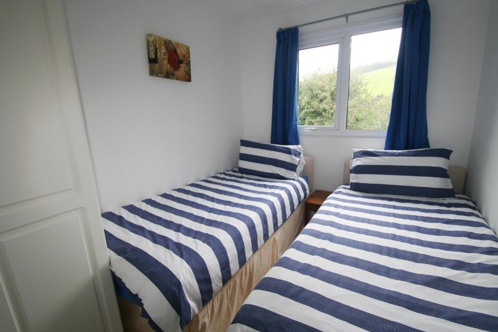 two beds in a room with a window at Freshwater Bay Holiday Cottages in Pembroke