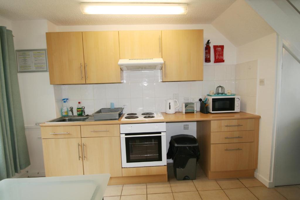 a small kitchen with wooden cabinets and a microwave at Freshwater Bay Holiday Cottages in Pembroke
