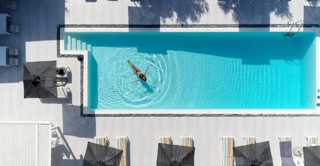 eine Person, die in einem Pool auf einem Gebäude schwimmt in der Unterkunft Naoussa Hills Boutique Resort- Adults Only (13+) in Naoussa