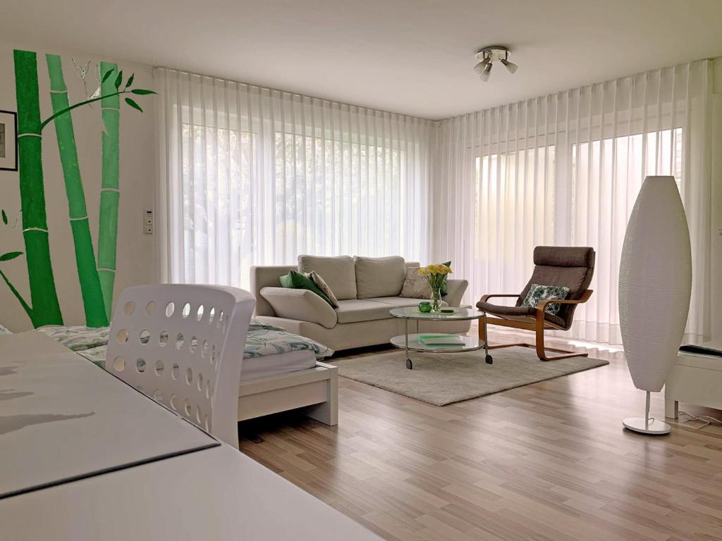 - un salon avec un canapé et une chaise dans l'établissement Ferienwohnung Zimmergrün am Nordpark, à Mönchengladbach