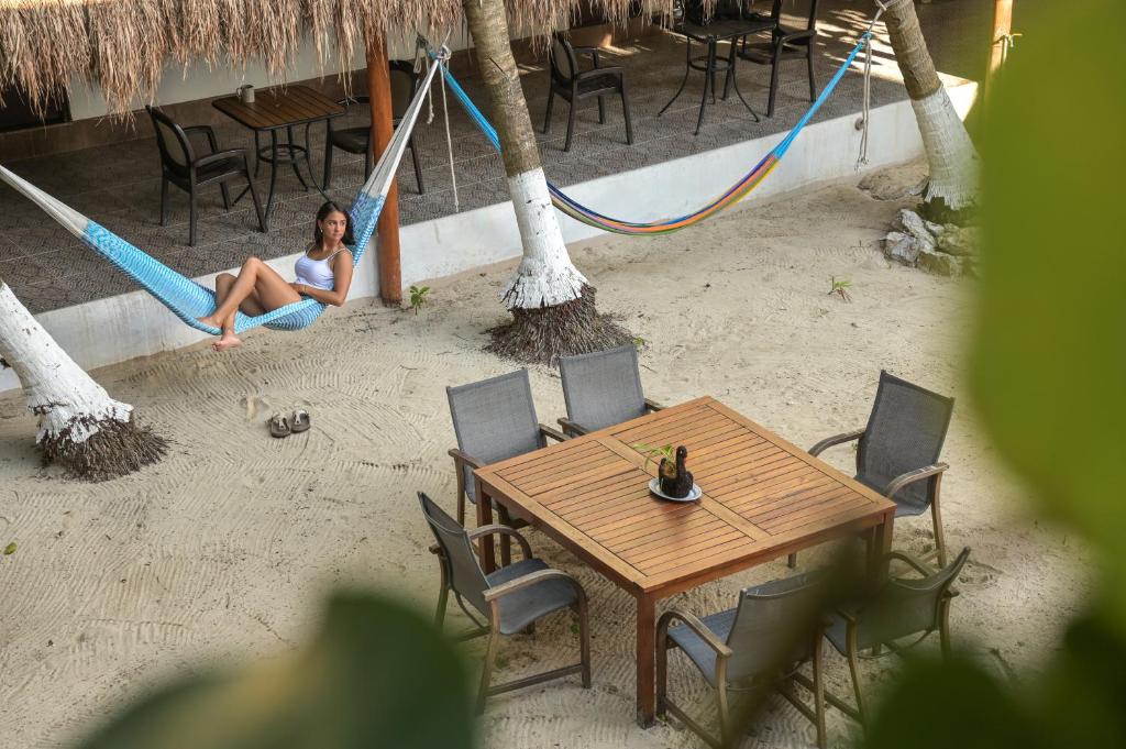 a woman sitting on a hammock on the beach at Kinta Kan Cabañas Hotel Playa del Carmen in Playa del Carmen
