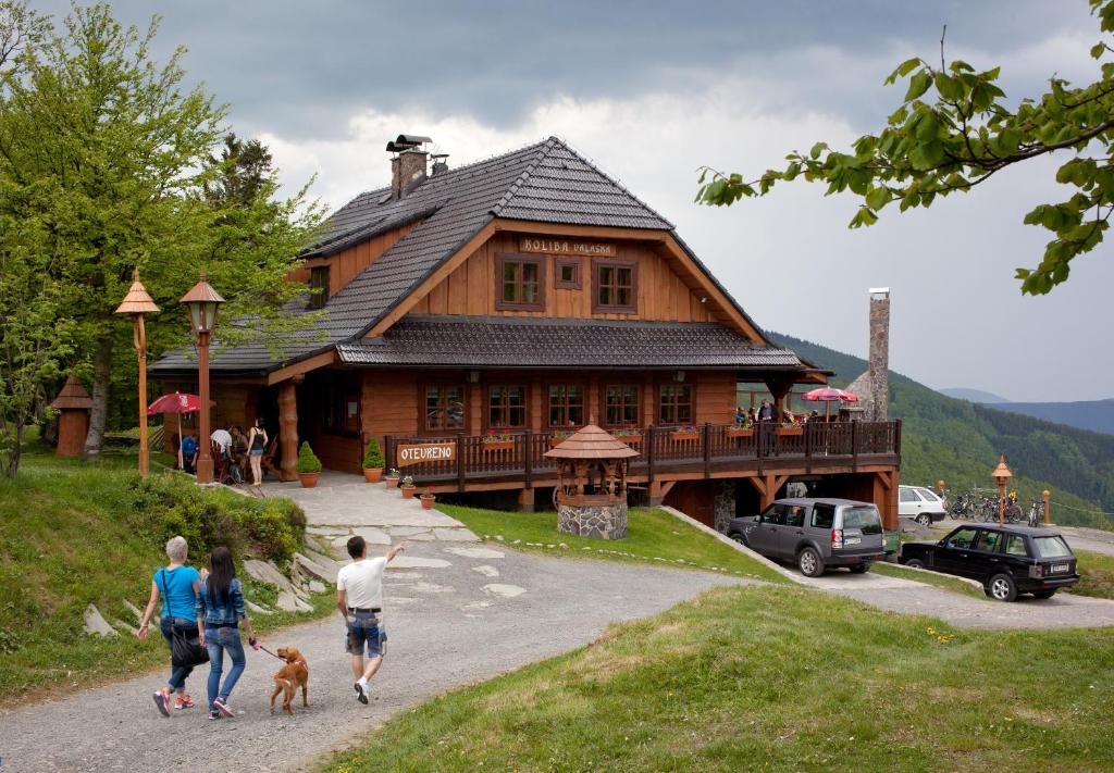 a group of people walking a dog in front of a house at Koliba Valaška in Trojanovice